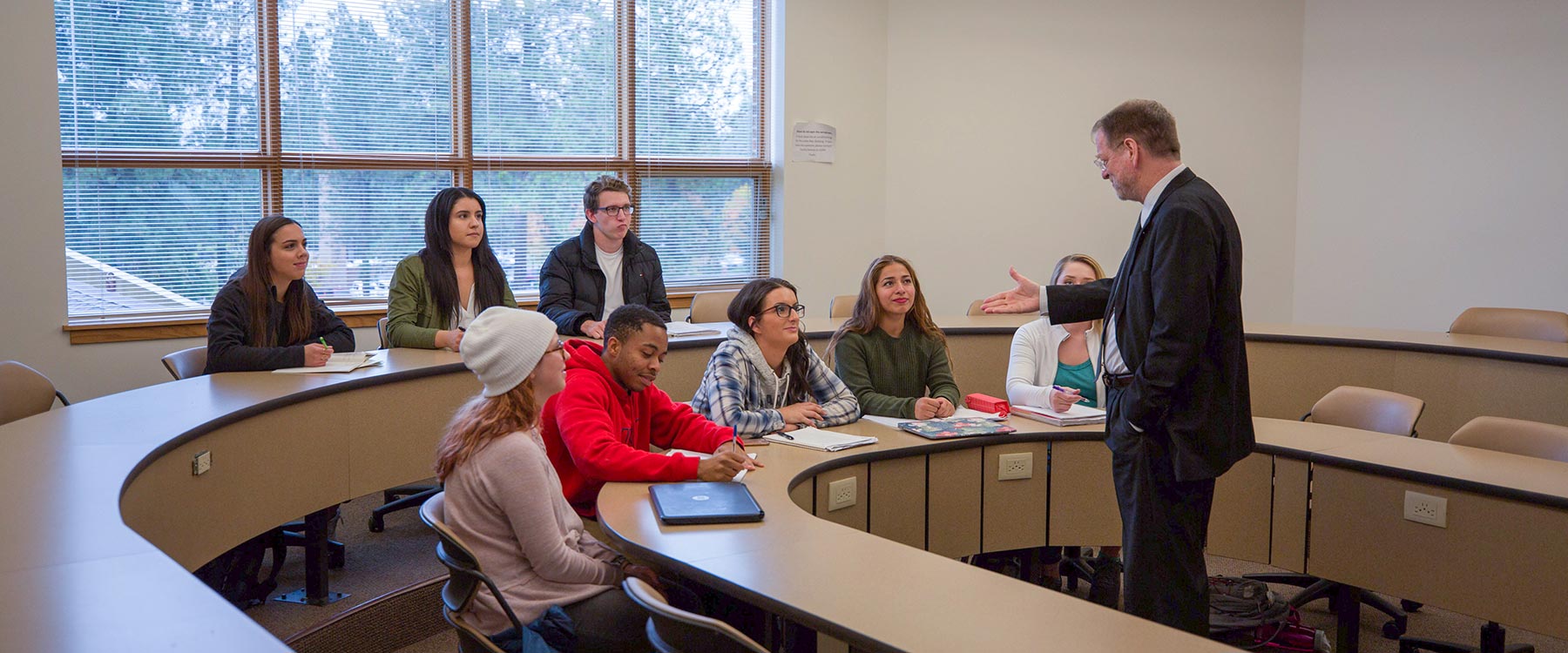 Students sit in tiered rows in a classroom as Professor Forrest Baird faces them, delivering a philosophy lecture. 