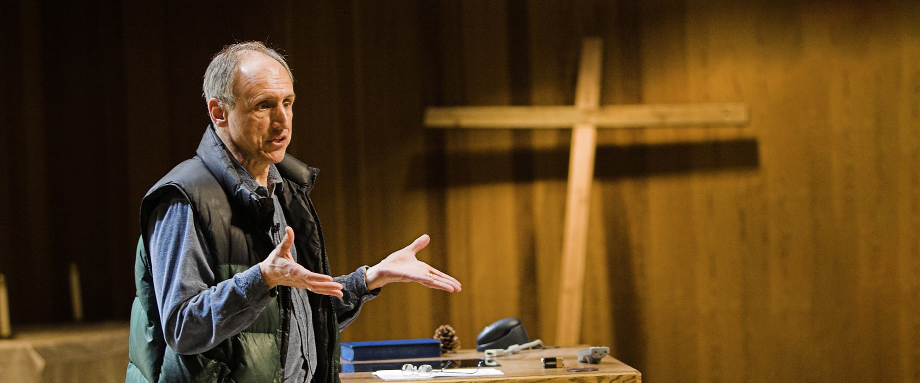 Professor Jerry Sittser gestures with outstretched hands during a theology lecture in the chapel.