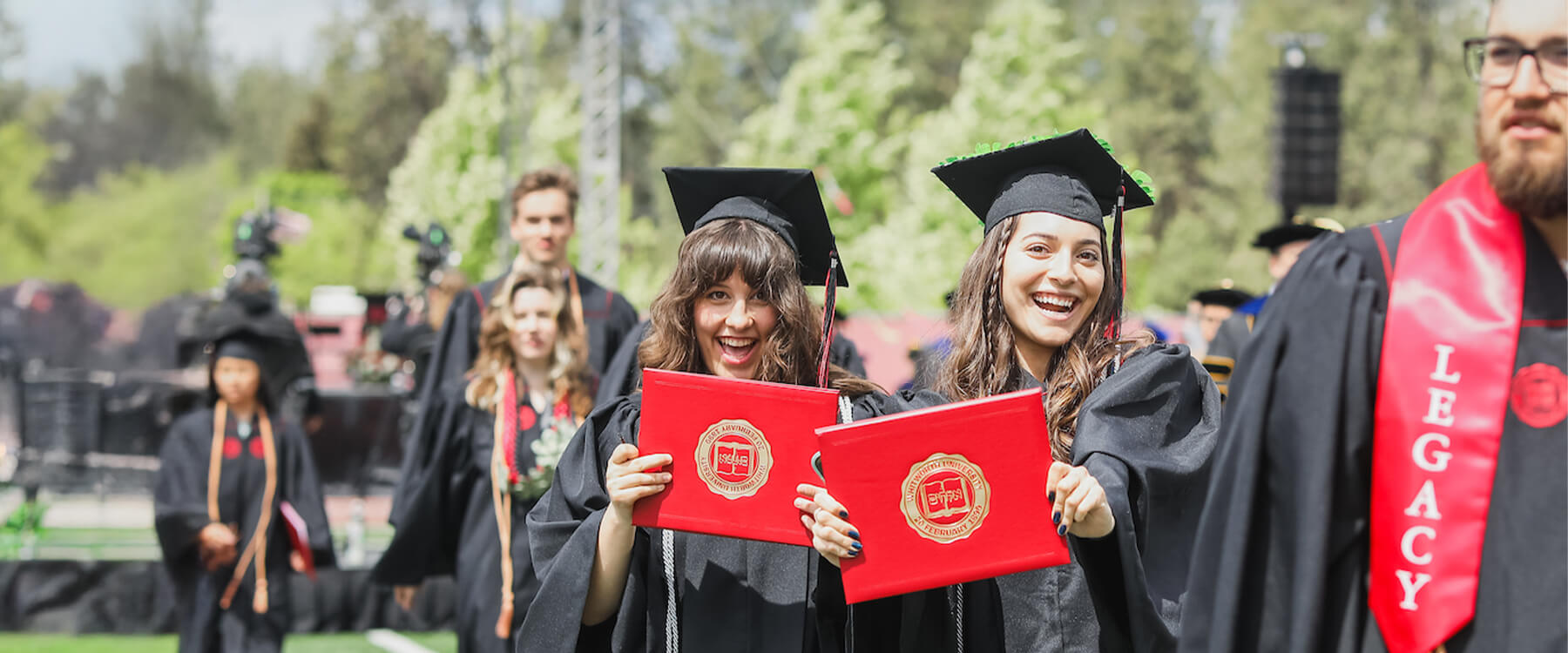 Graduates smiling and showing off diplomas