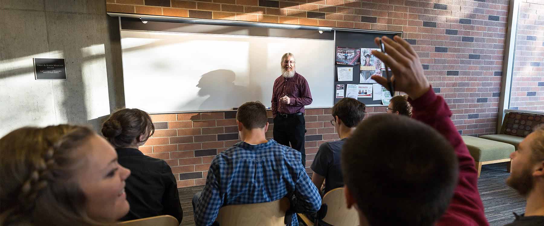 A student raises his hand in an engineering classroom