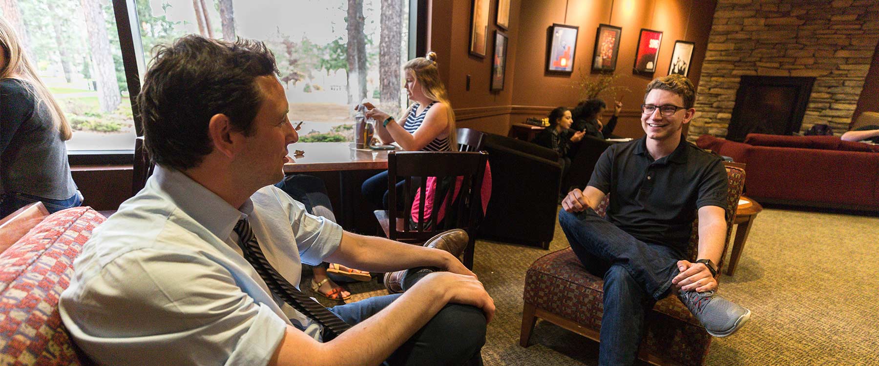 Assistant Professor David Sloan sits across from and talks with a student in the Mind and Hearth coffee shop.