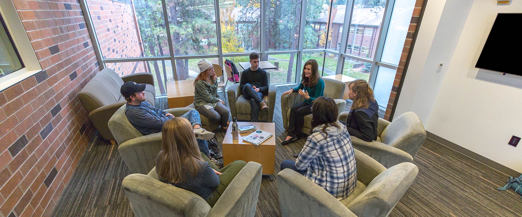 Associate Professor Elizabeth Campbell sits with a group of psychology students in a circle of armchairs.