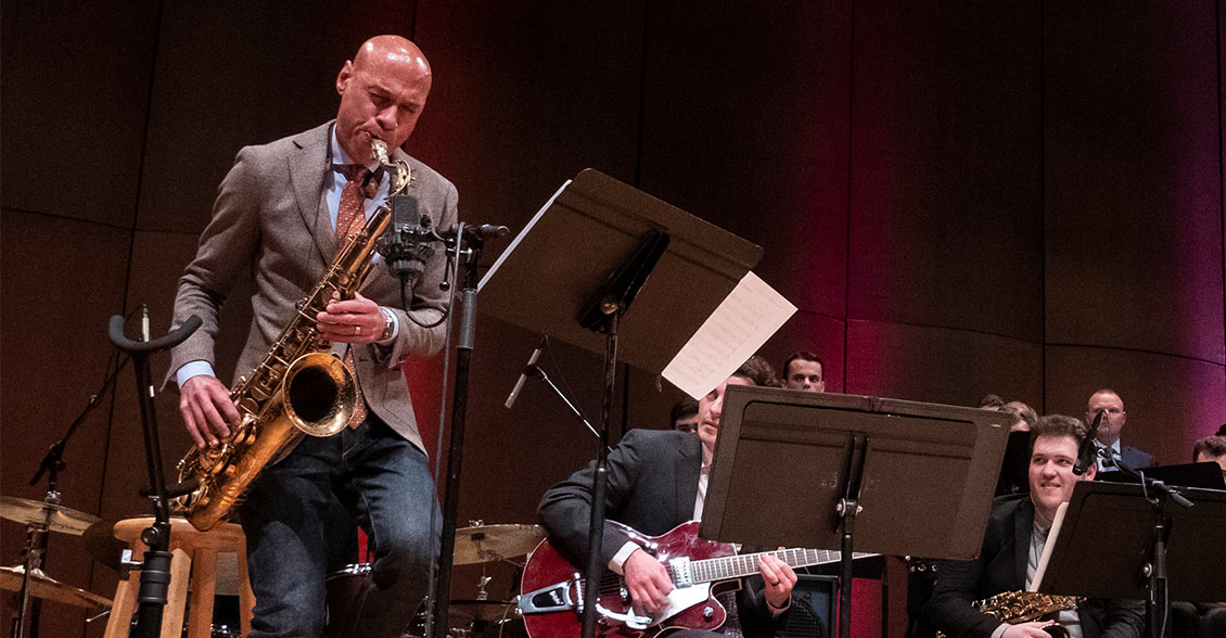 Joshua Redman playing the saxophone while students watch amazed.