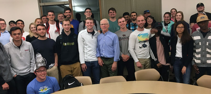 President Emeritus Bill Robinson stands and smiles with a group of Whitworth business students.