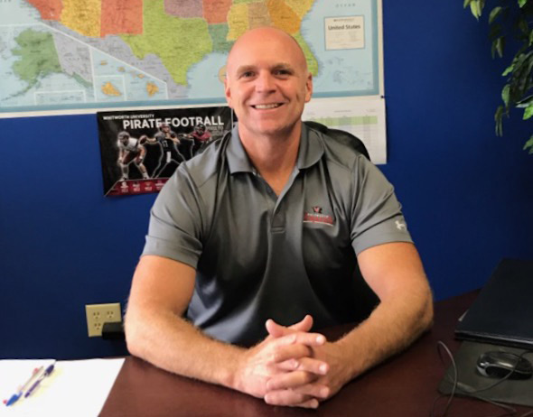 Blake Tucker sits behind a desk and smiles.