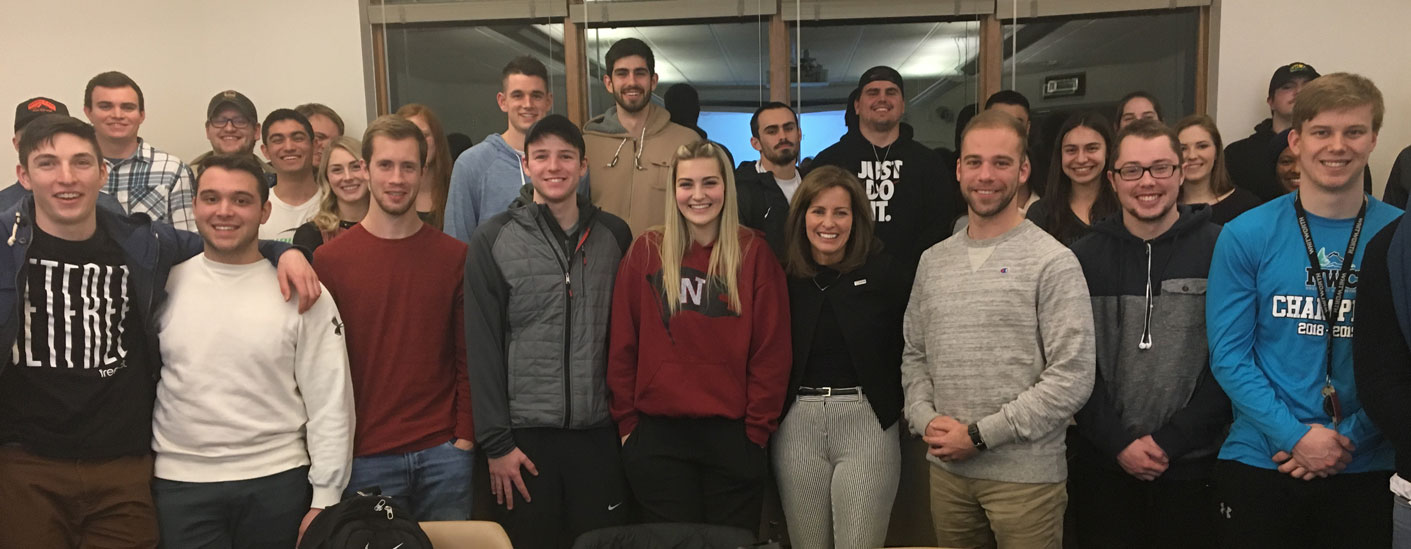 Linda Underwood and students pose, smiling, in front of a window in a classroom setting.