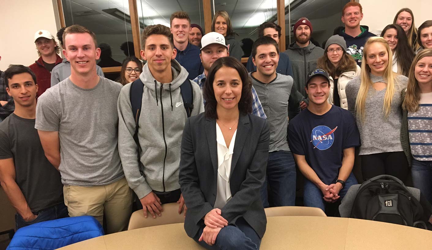 Shelly O'Quinn and students pose, smiling, around a semicircle desk.