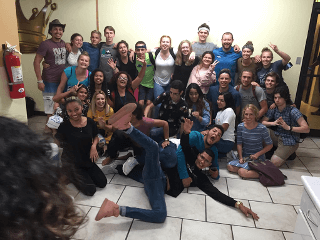 An animated group of students smiling and posing for a photo together indoors.