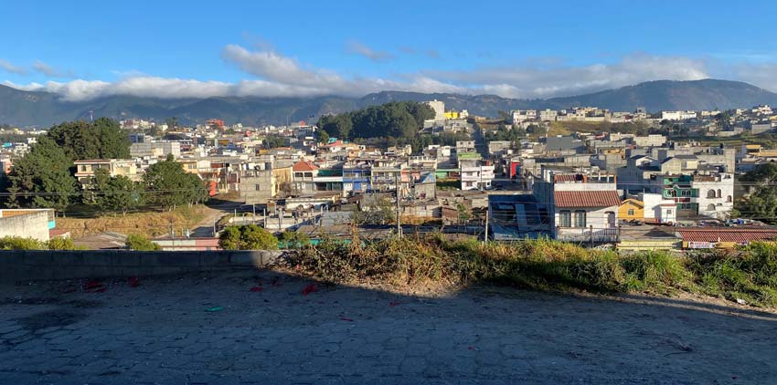 A picturesque view of a coastal town with various building styles, set within rolling hills.