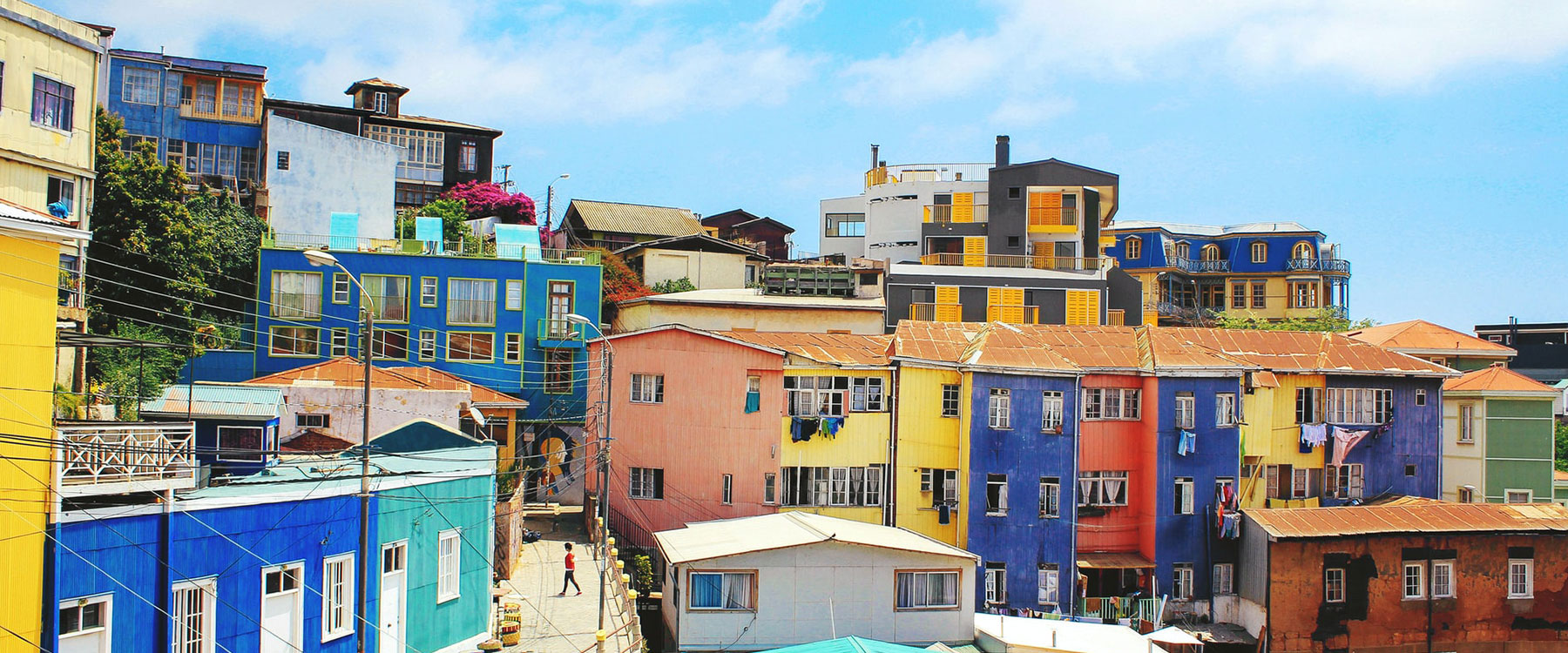 Colorful hillside houses under a blue sky, with vivid facades of blue, yellow, orange and red.