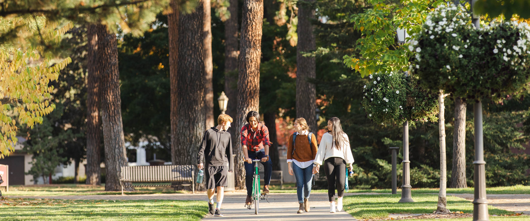 Students walk on campus at Whitworth. Evergreen trees in the background