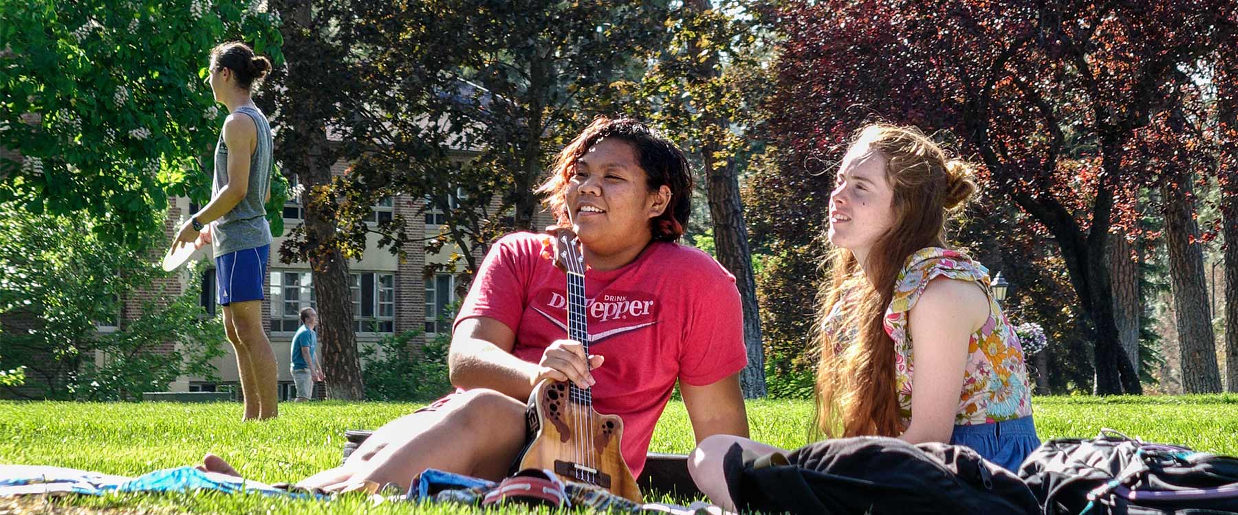 Two students sit in the grass in the loop.