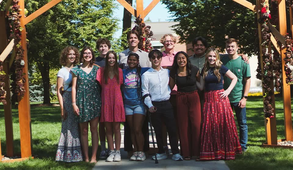 A group of students stand and pose together outdoors, all smiling.