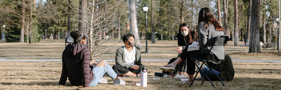 Students sit on campus and talk in a group.