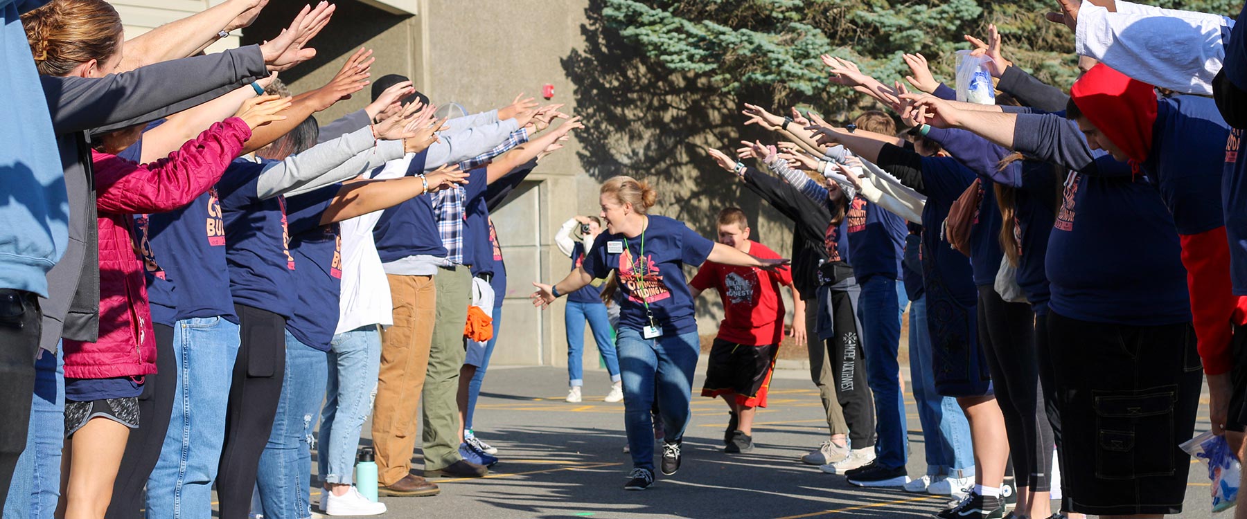 A person runs through a tunnel formed by people extending their arms, creating a cheerful and energetic atmosphere.