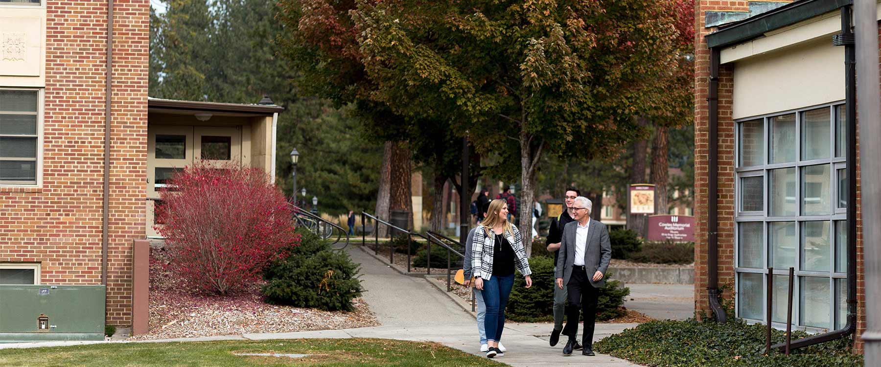 Professor Randall Michaelis walks with a small group of students on a path through campus.