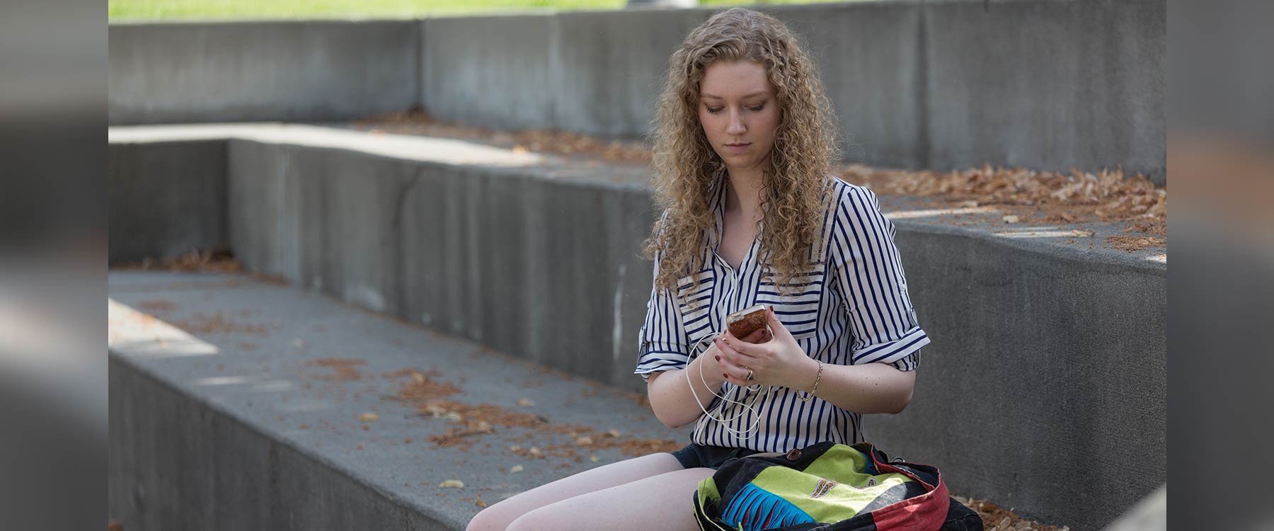 Victoria sits on the steps outside Cowles Memorial Library and looks down at her phone.