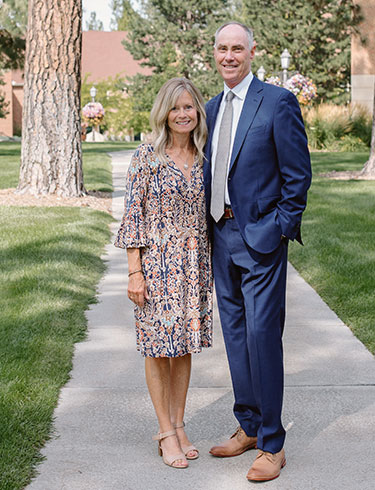 Scott and Janice McQuilkin post together near a pillar outdoors.