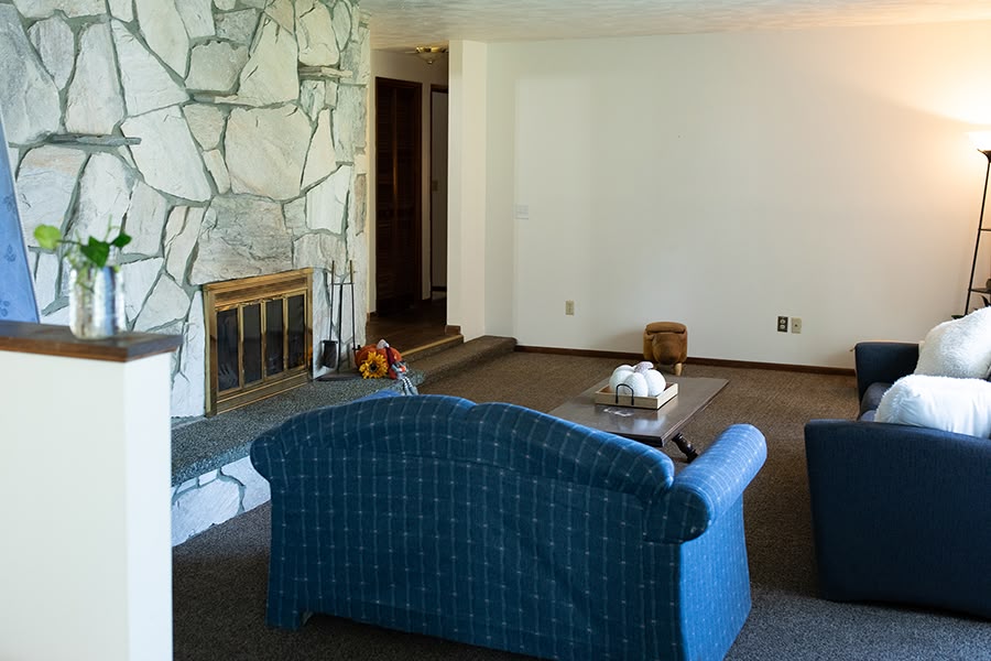 Cozy living room with a white stone fireplace, two blue sofas and a wooded coffee table.