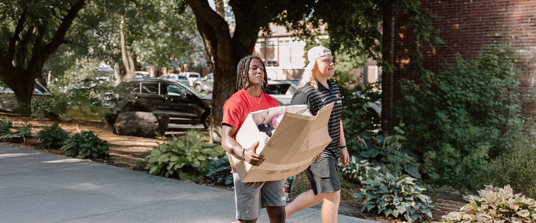 A student and two parents unpack household supplies from the back of an SUV.
