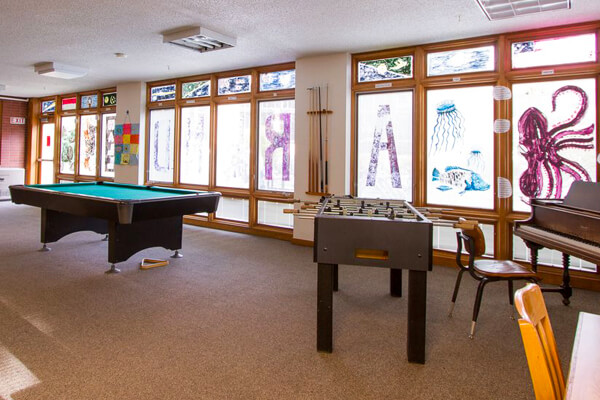 The Arrend Hall common room. Ping-pong, pool, and foosball tables are spread throughout the room, as well as a piano.