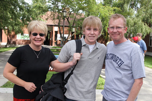 A student and his parents pose together outside of Baldwin-Jenkins.