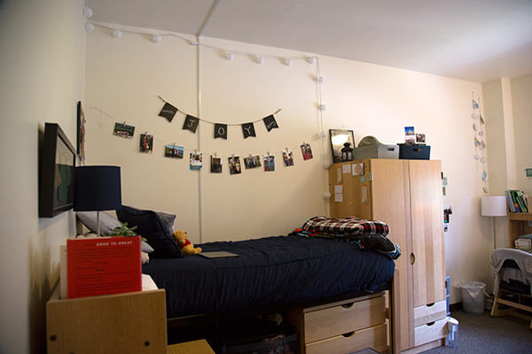 A Duvall Hall dorm room with a bed, wardrobe, and hanging pictures.