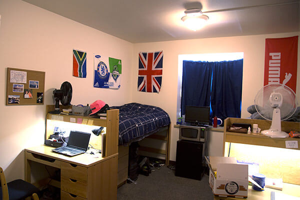 A Duvall Hall dorm room with a bed, desk, and mini-fridge to one side.