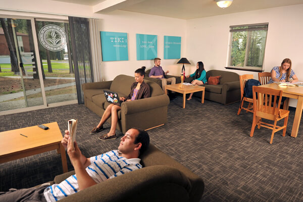 Students are scattered throughout a common room reading, talking and studying on couches.