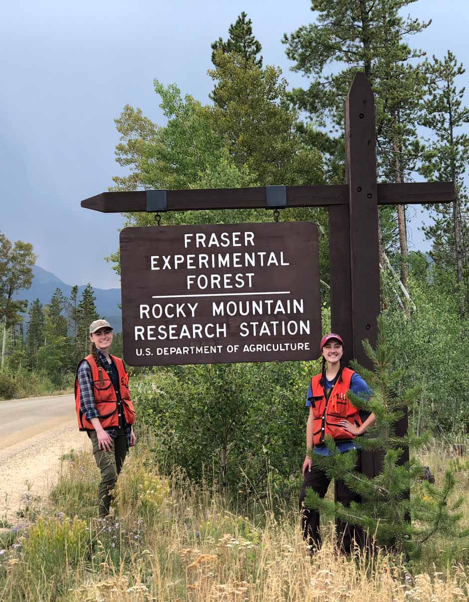 Sahale Riedel stands on one side of the Fraser Experimental Forest sign.