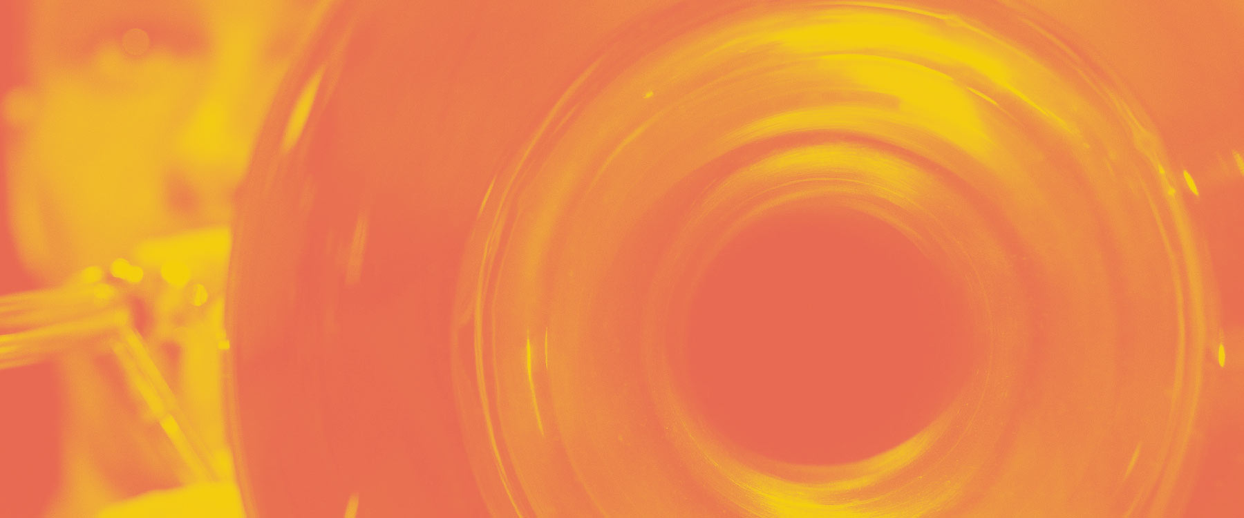 Close-up, vibrant orange and yellow-toned image of a brass instrument, focusing on the bell.