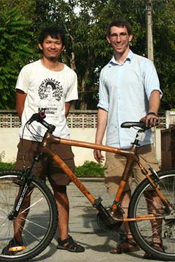 Jeffrey and a friend stand with a bicycle, smiling at the camera.