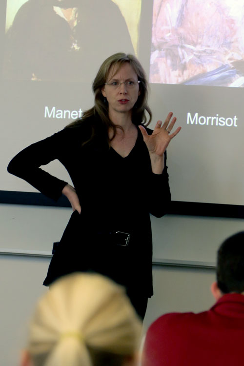 Meredith Shimizu stands at the front of a classroom lecturing.