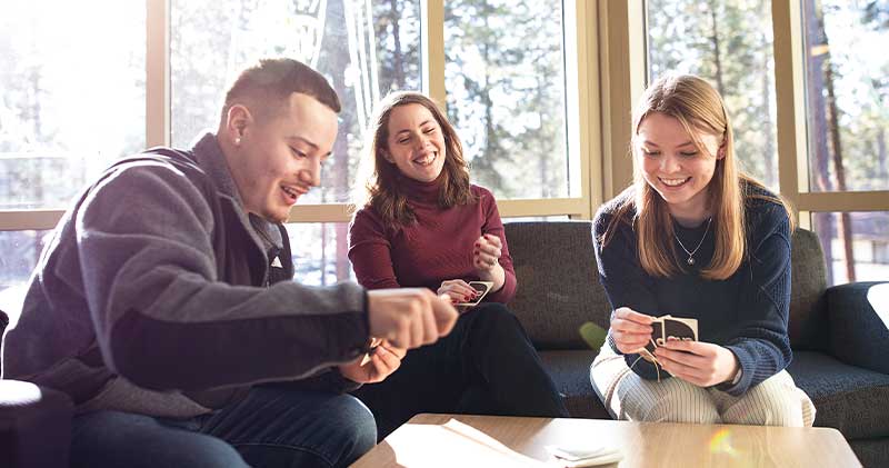 Three students playing cards around a table
