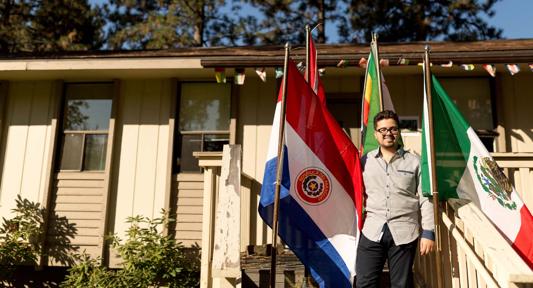 A student smiling, standing among flags