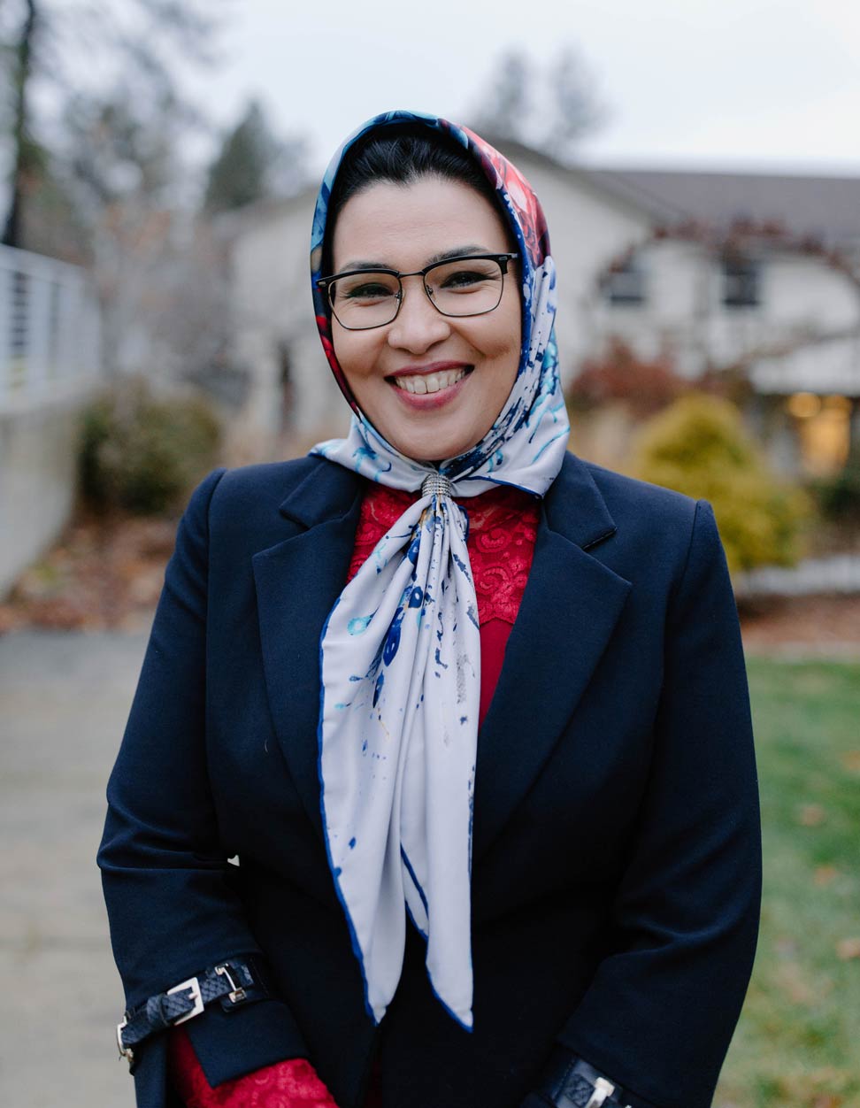 Sorayya Mohammadi stands outside, wearing a headscarf, on an overcast day with trees in the background.