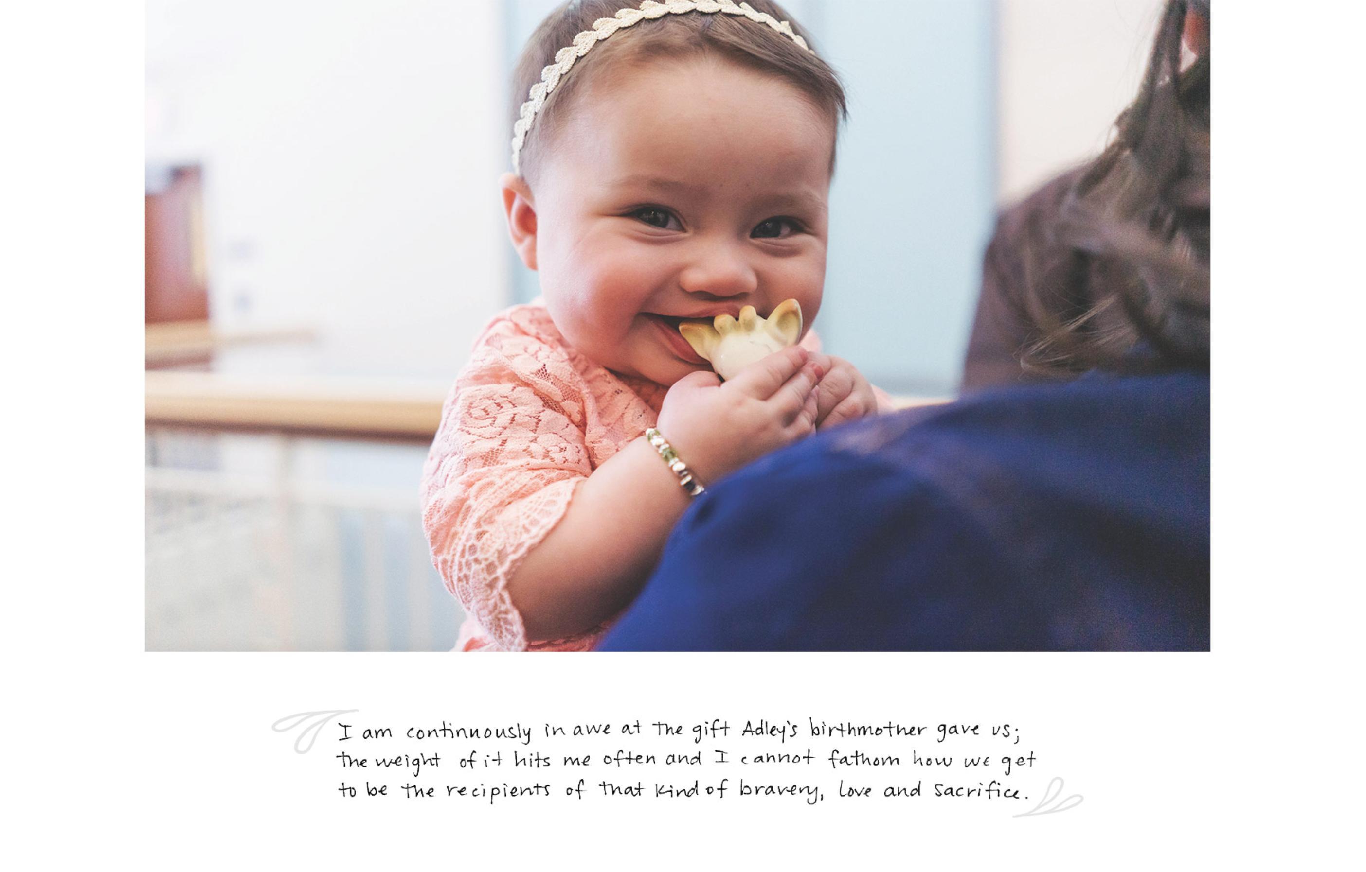 A smiling baby in a pink outfit holds a flower, with a handwritten message in the lower half of the image.