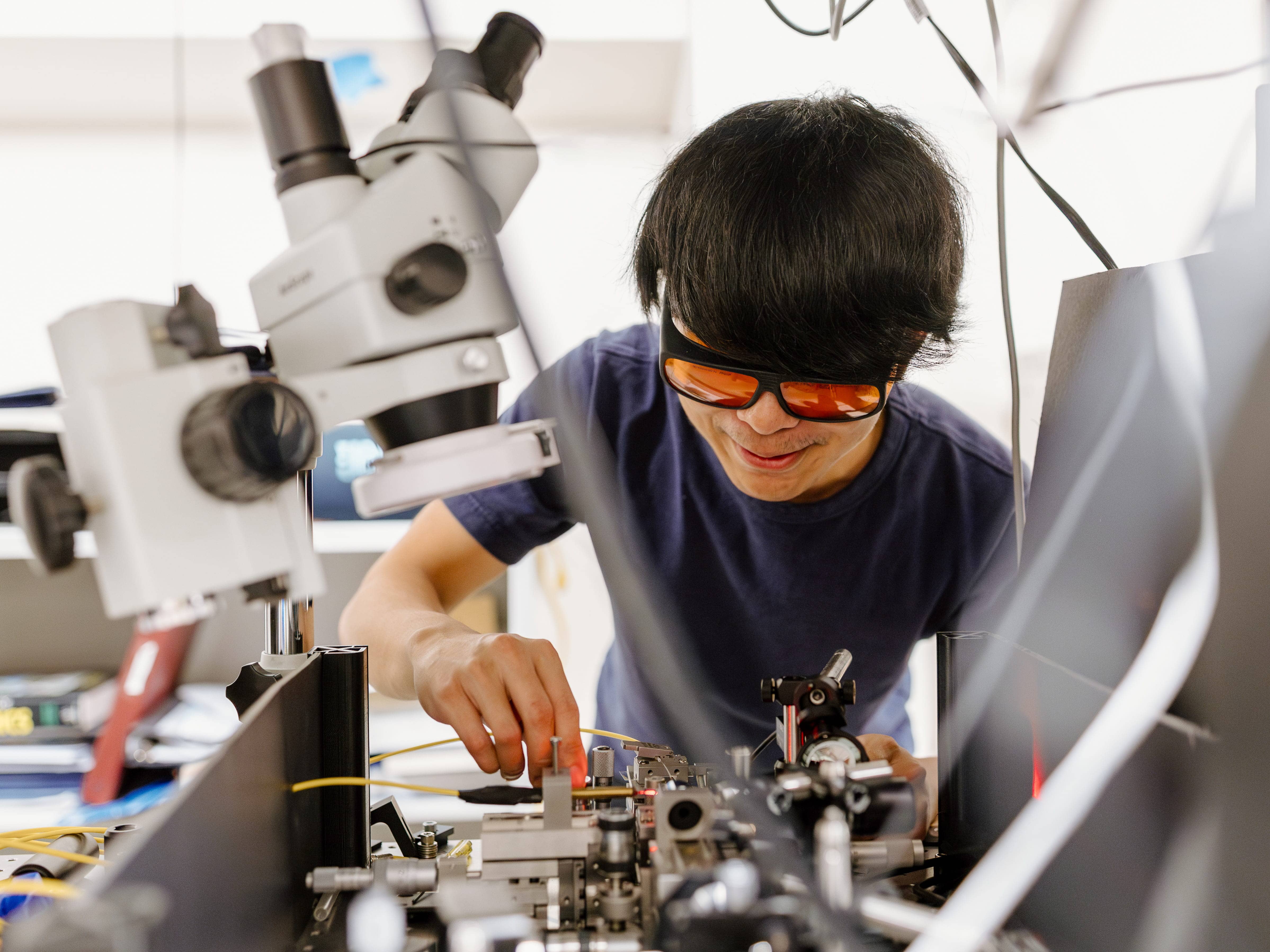 A student, wearing goggles, works in an electronics lab.