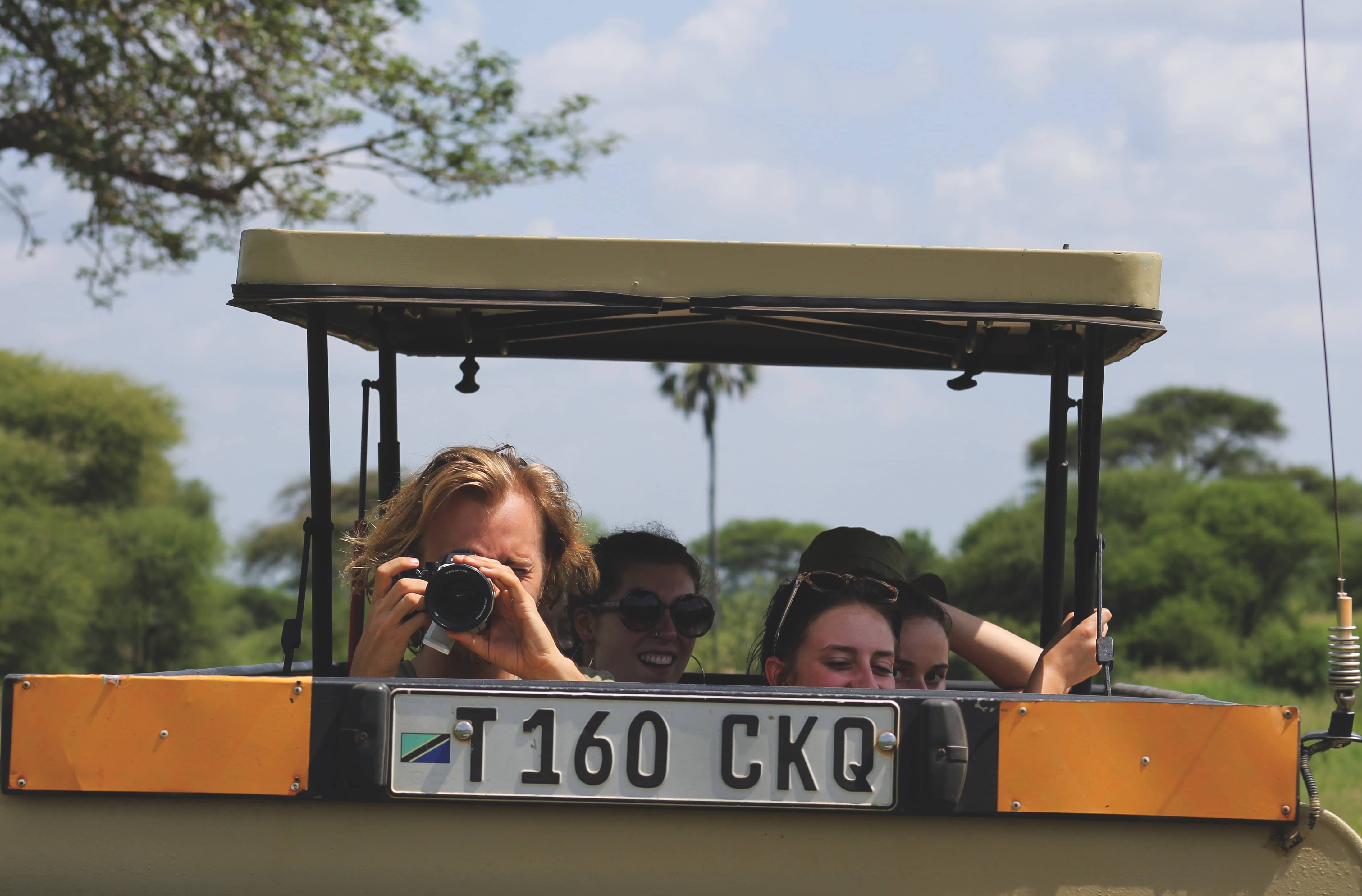 Several students enjoy the sights and take photos from an open-air vehicle.