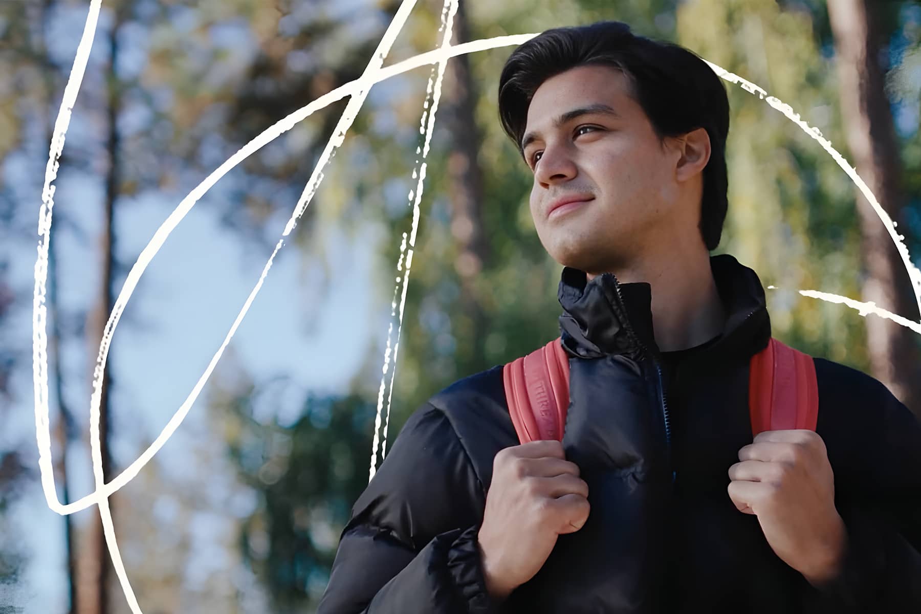 A student stands outside in nature with a backpack.