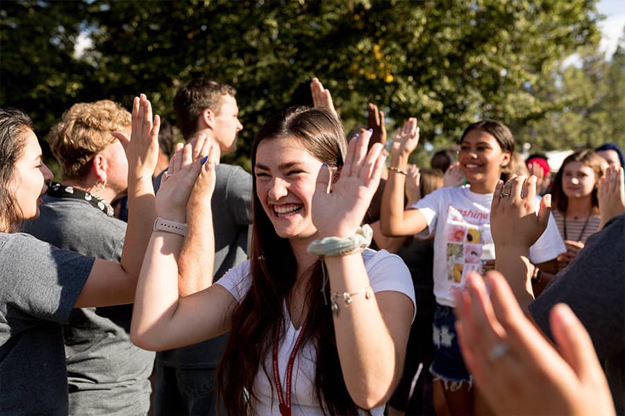 Rows of students high-five each other as they pass by, smiling.