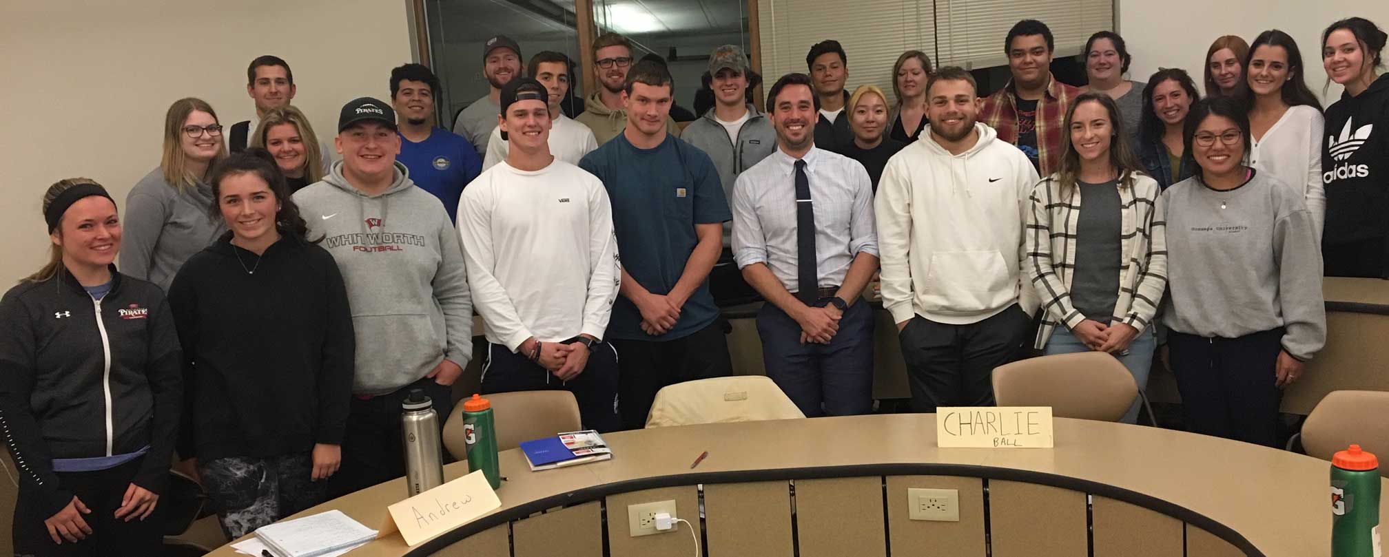 Austin Vierra and students pose, smiling, around a semicircle desk.