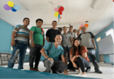 A group of people posing together in a decorated indoor space with balloons on the ceiling.
