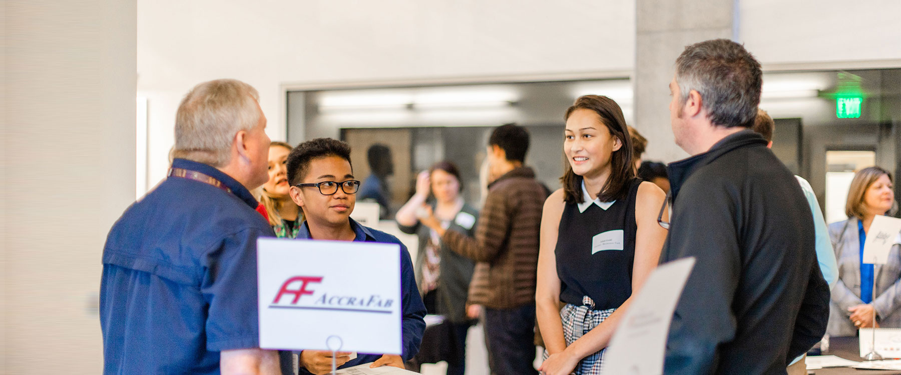 Students and employers networking at a career fair near a table with a sign reading 