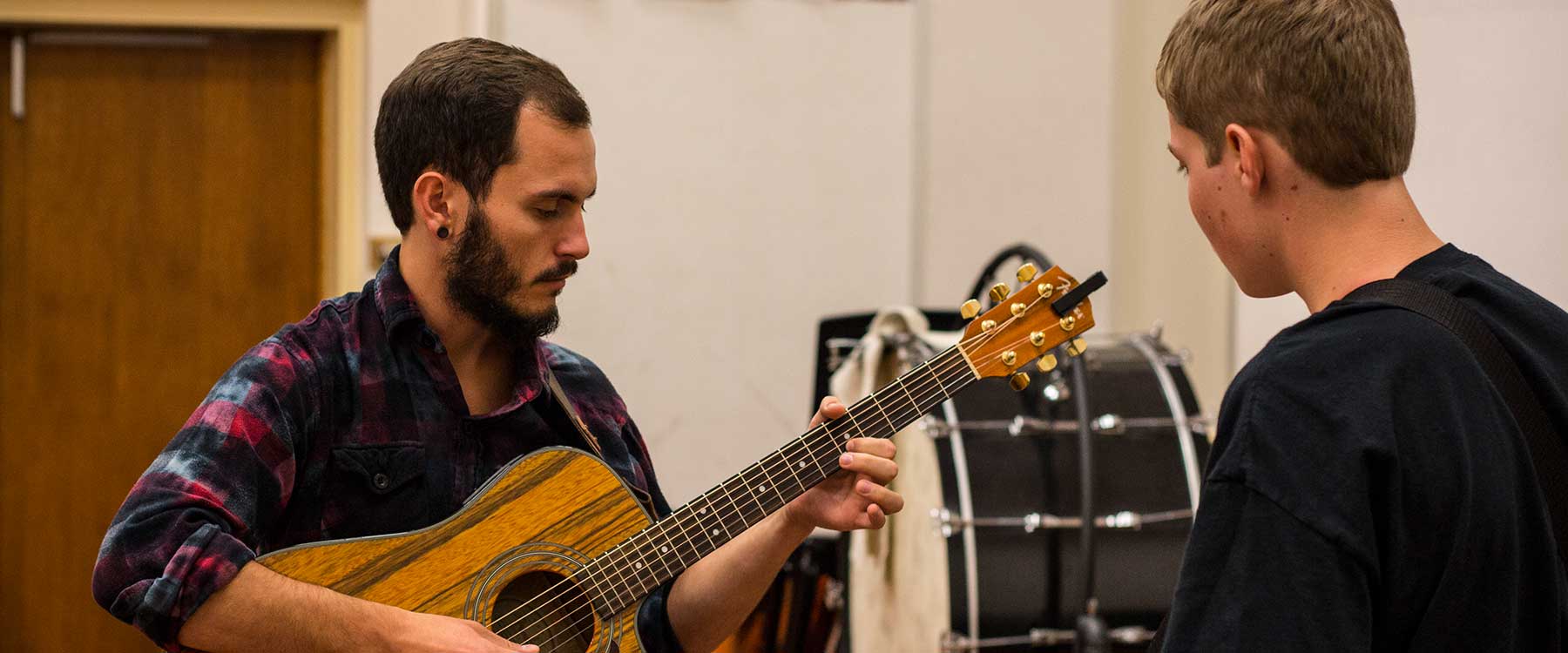 Close-up of two students practicing worship music. One plays a guitar.
