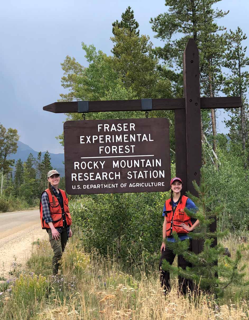 Two students in orange vests stand beside the