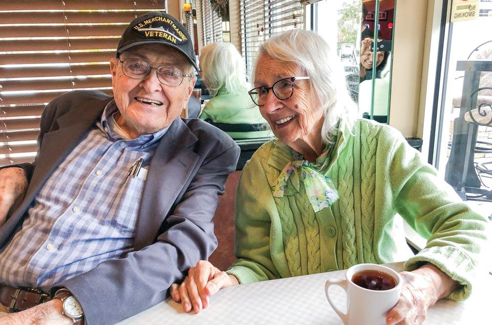 Jack and Gerry Eccles sit at a diner table by a window with coffee, laughing.