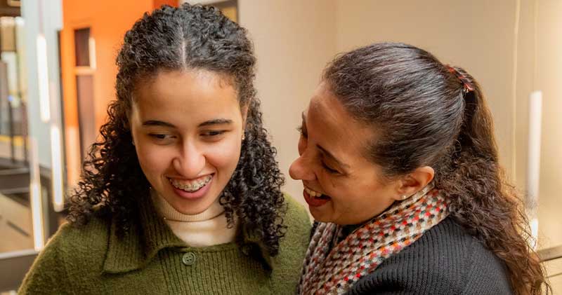 Two people standing close together indoors, smiling and sharing a warm engaged moment