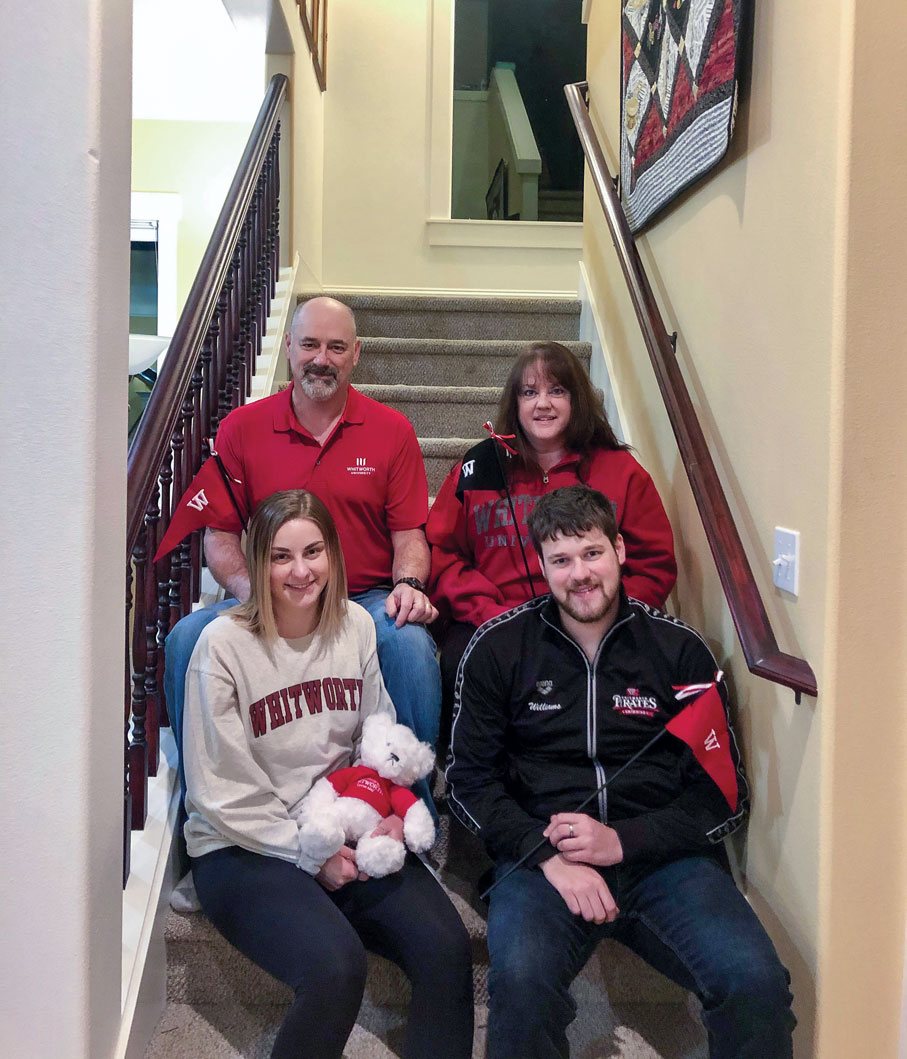 Four members of the Williams family, two adults and two grown kids, sit on an interior stairwell together, smiling.